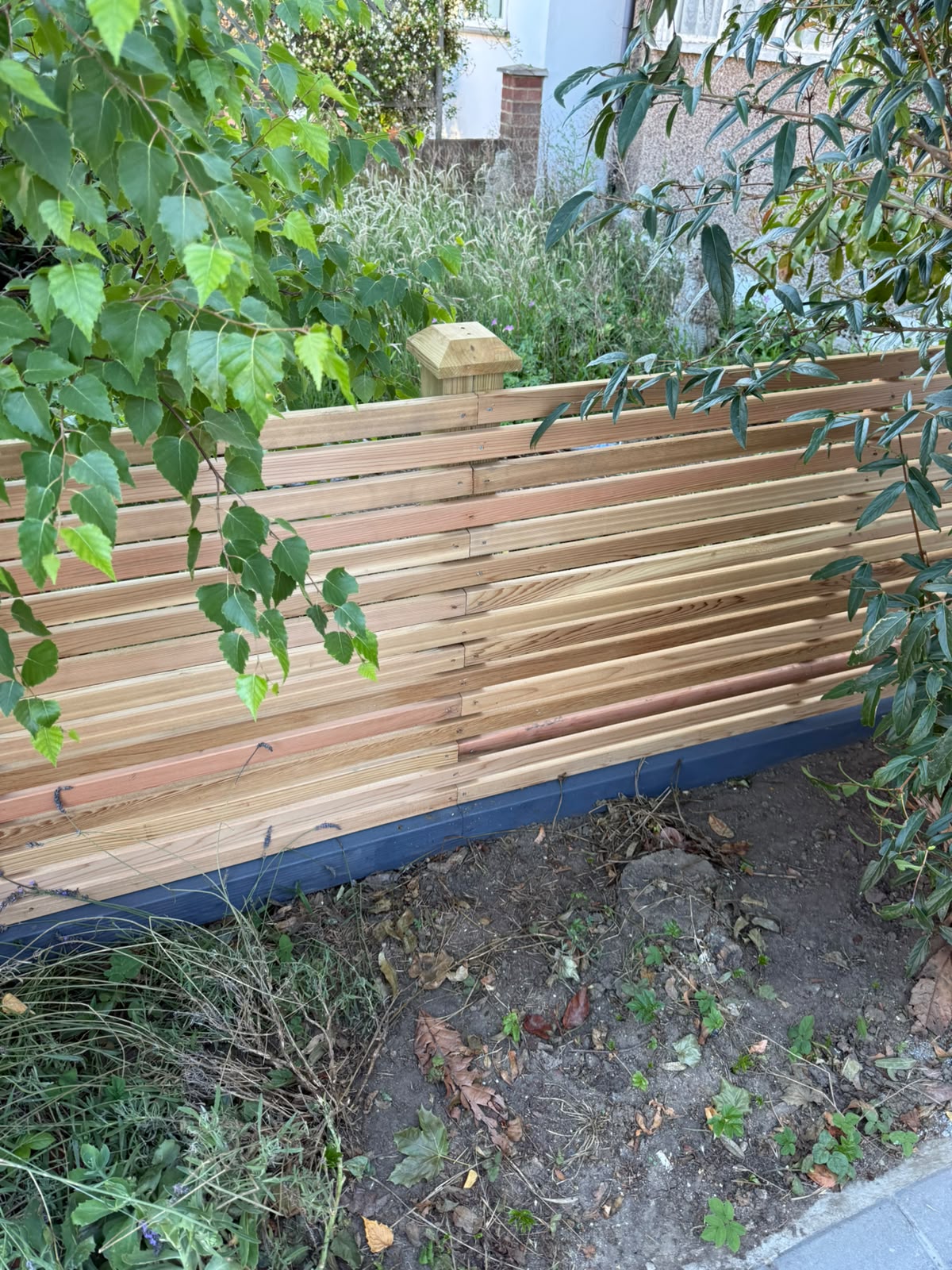 New slatted timber fence installed in a garden