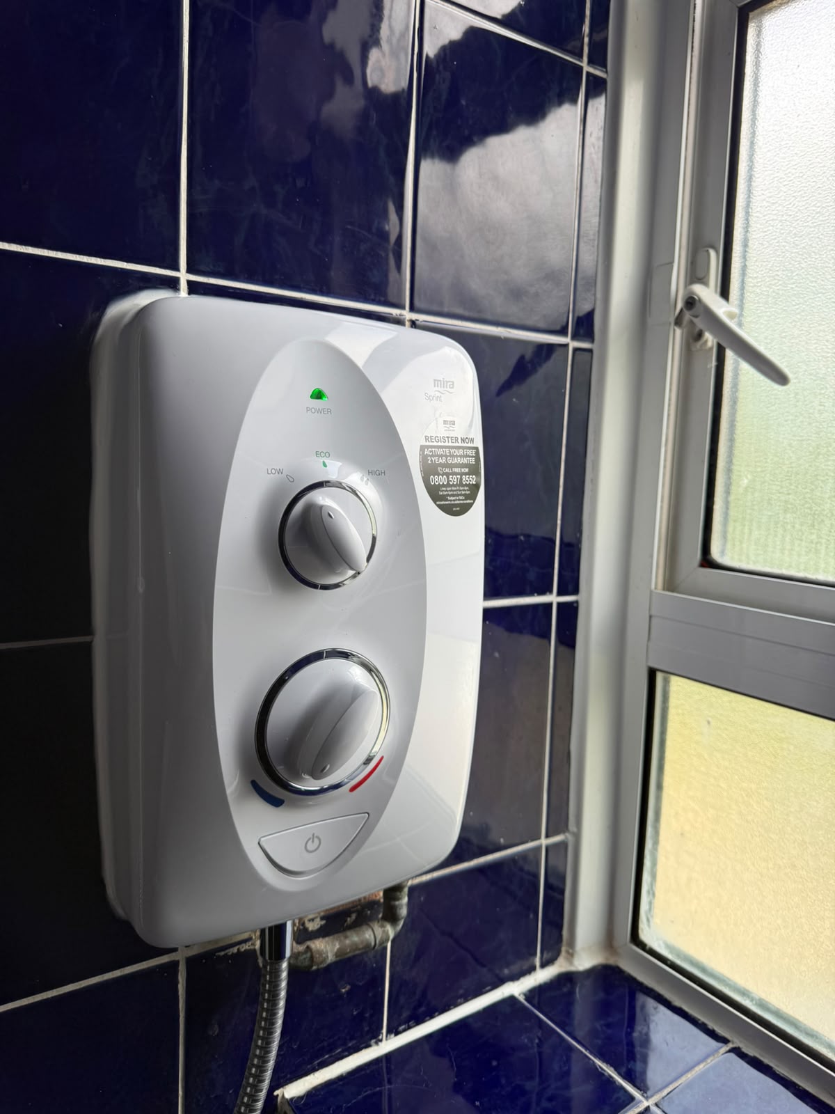 Electric shower unit installed on a tiled wall