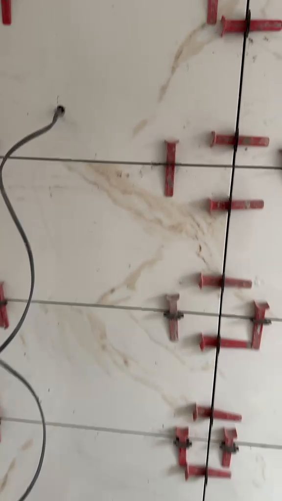 Large-format bathroom wall tiling in progress with levelling clips